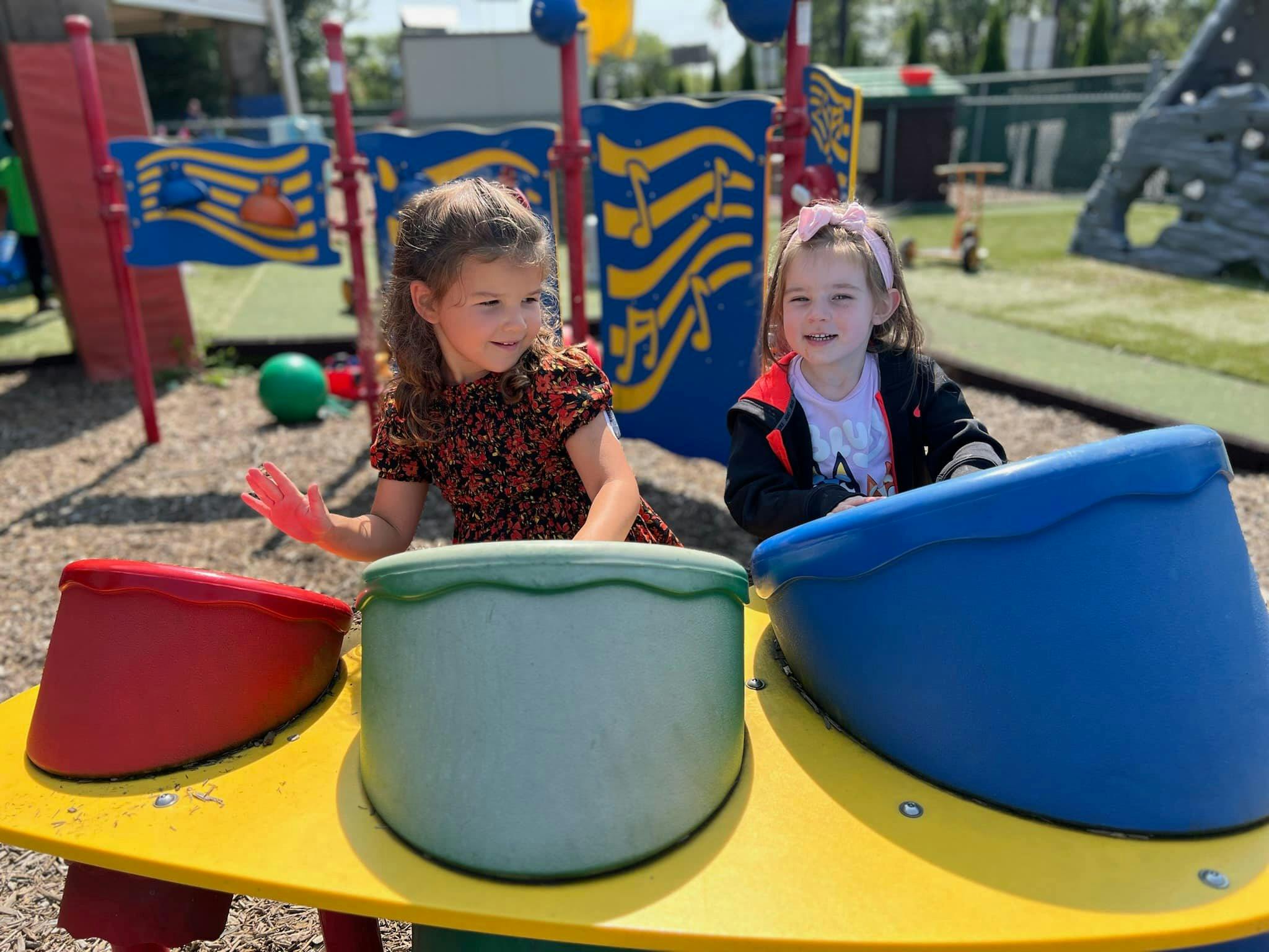 Two children playing with colorful drums on a playground