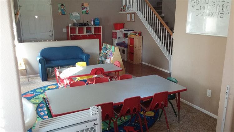 Classroom with small tables and chairs, blue couch, and staircase