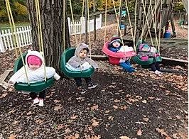 Four children in swings on a playground