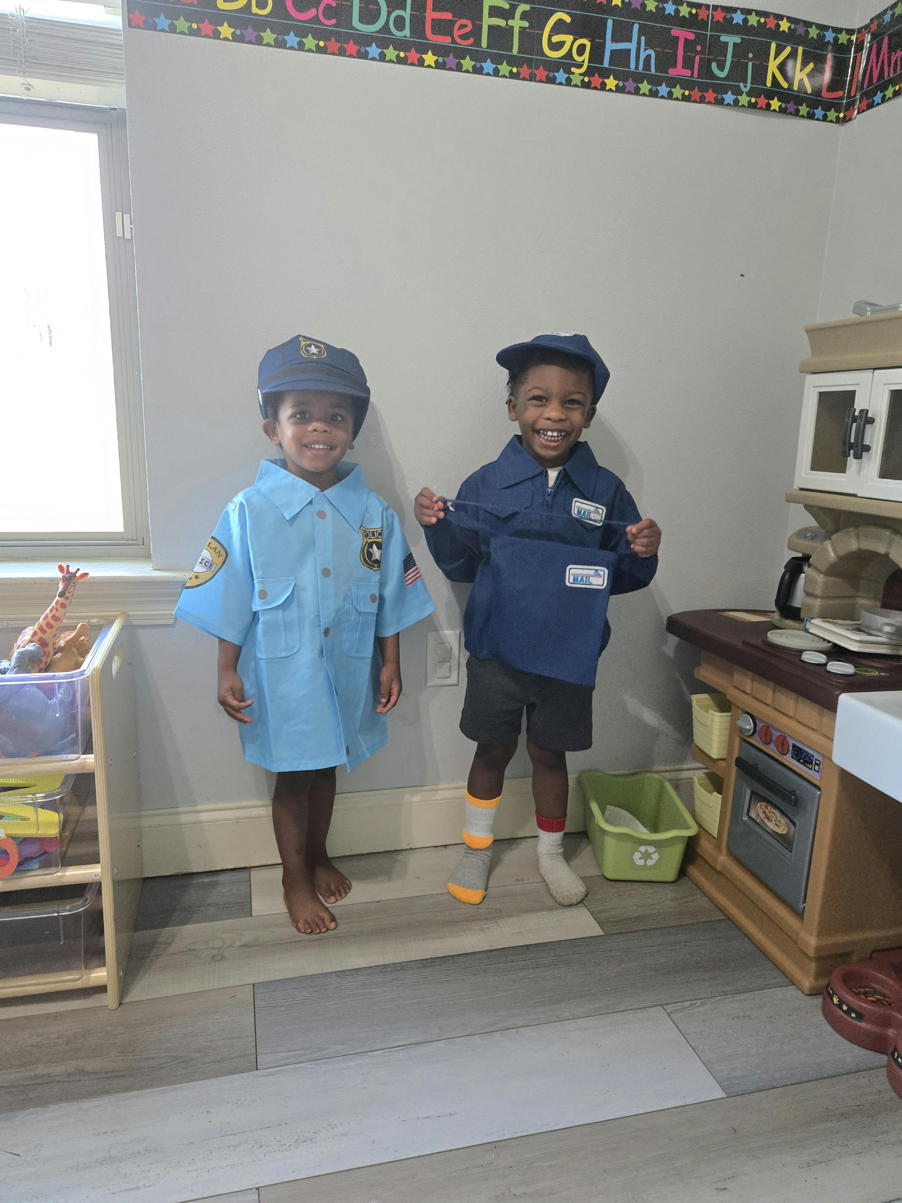 Two children in costume, one in a light blue uniform, one in a dark blue uniform