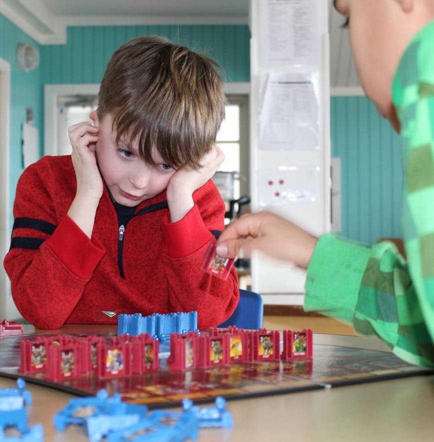 Child playing a board game with another person