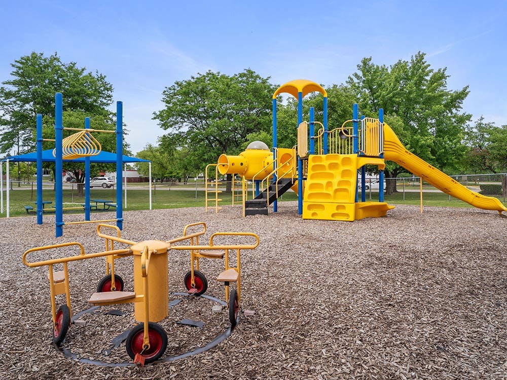 Playground with yellow slides, climbing equipment, and a merry-go-round