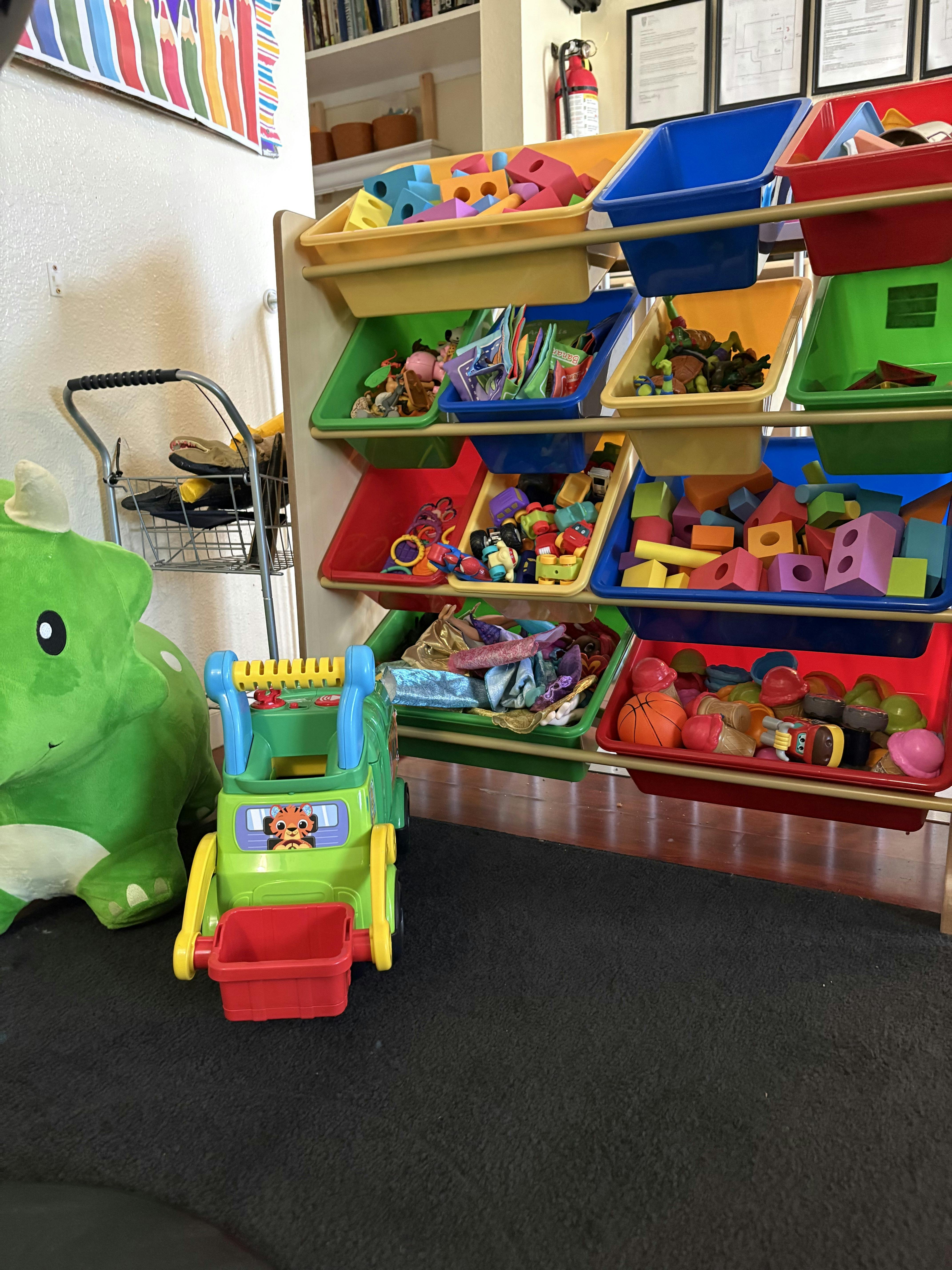 Colorful toy storage bins filled with building blocks, dolls, and other toys
