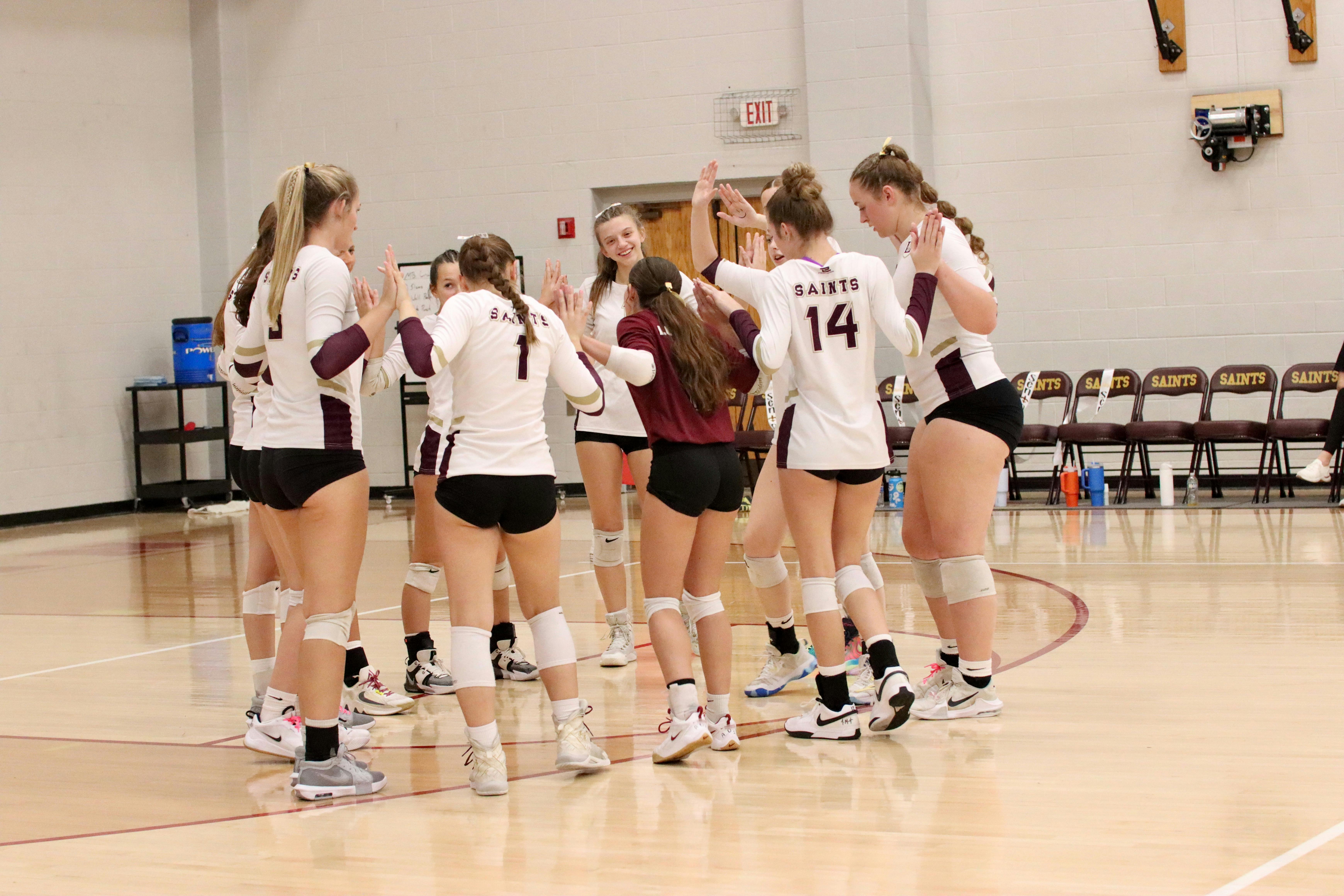 Volleyball team huddled together on a court