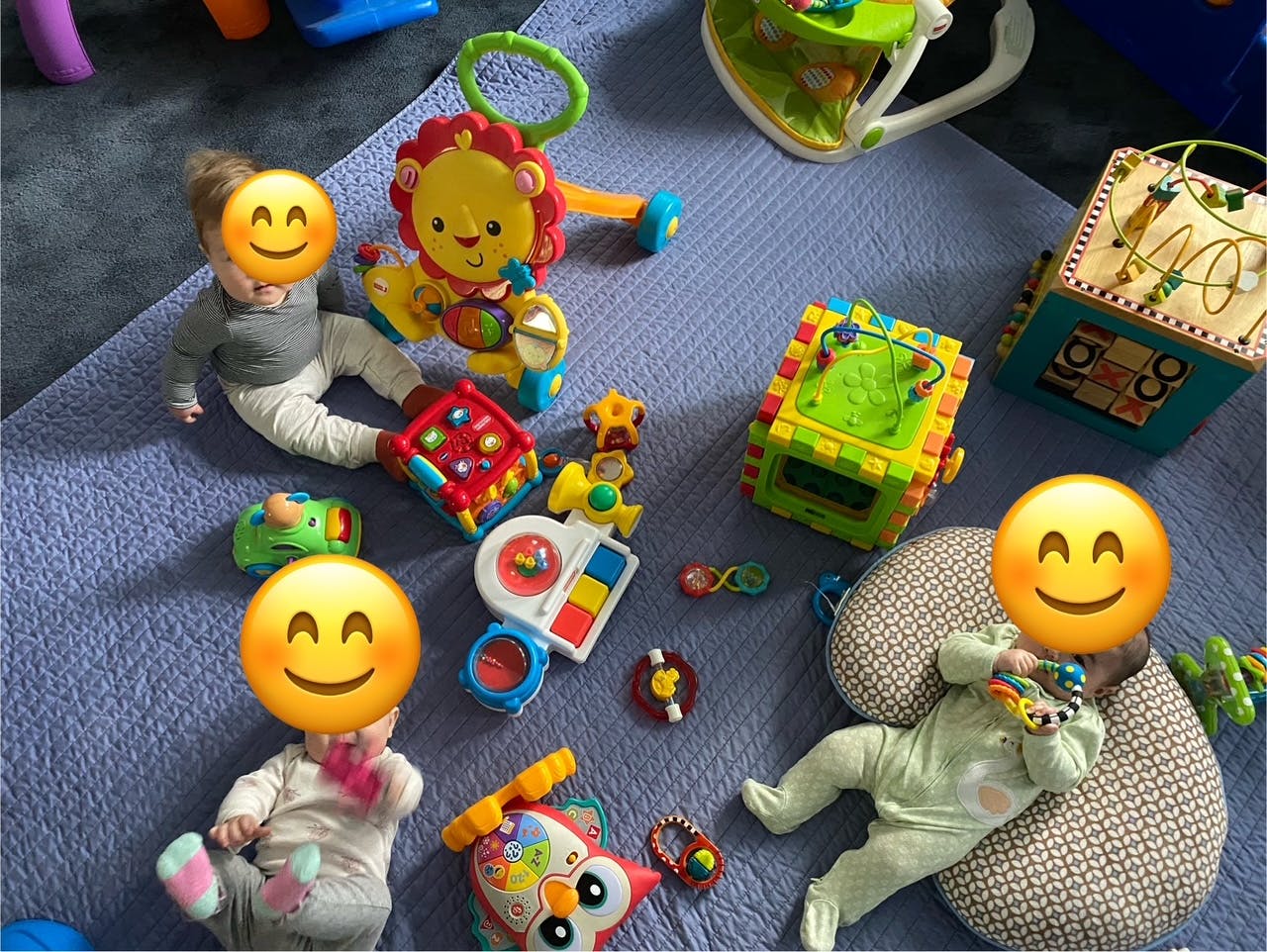 Multiple children playing with various toys on a mat