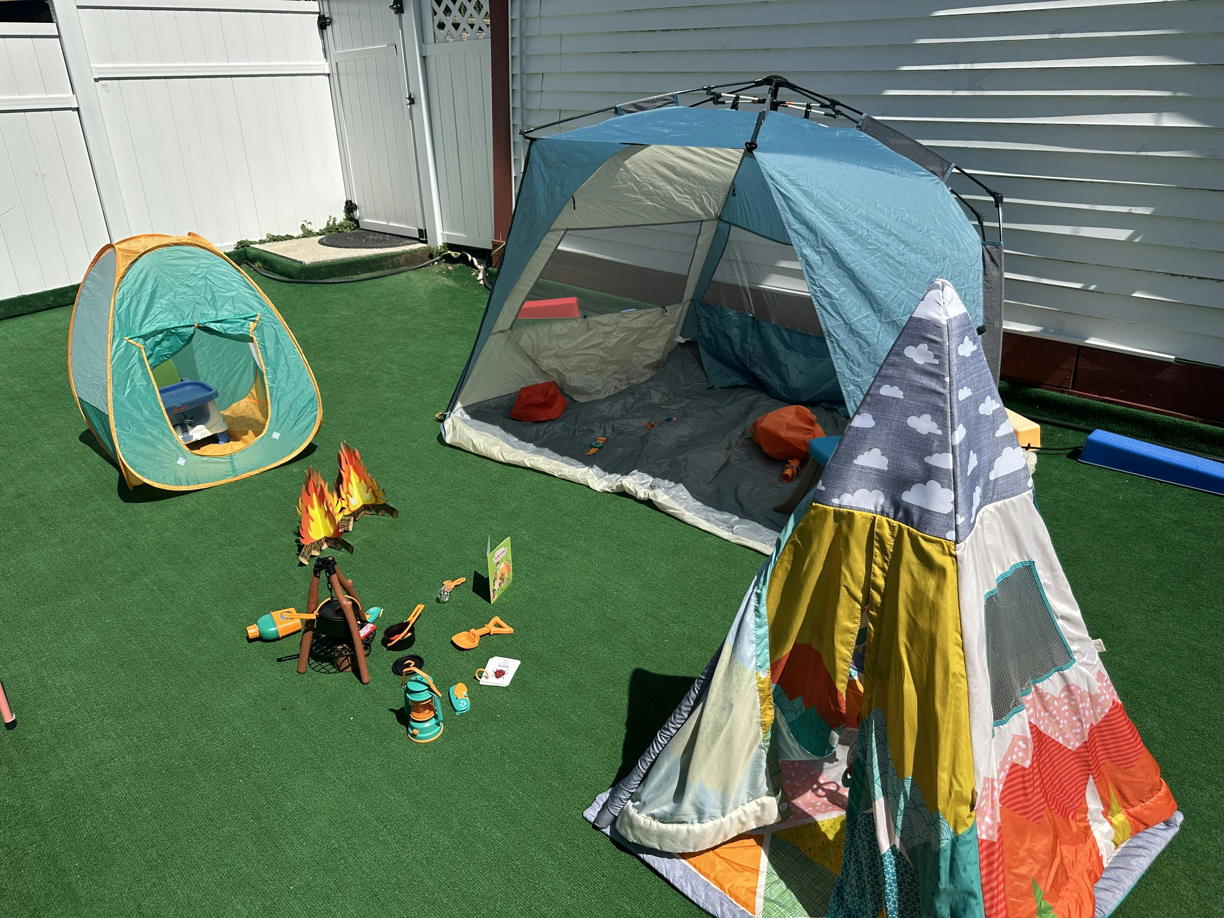 Two small tents and a play campfire on green turf