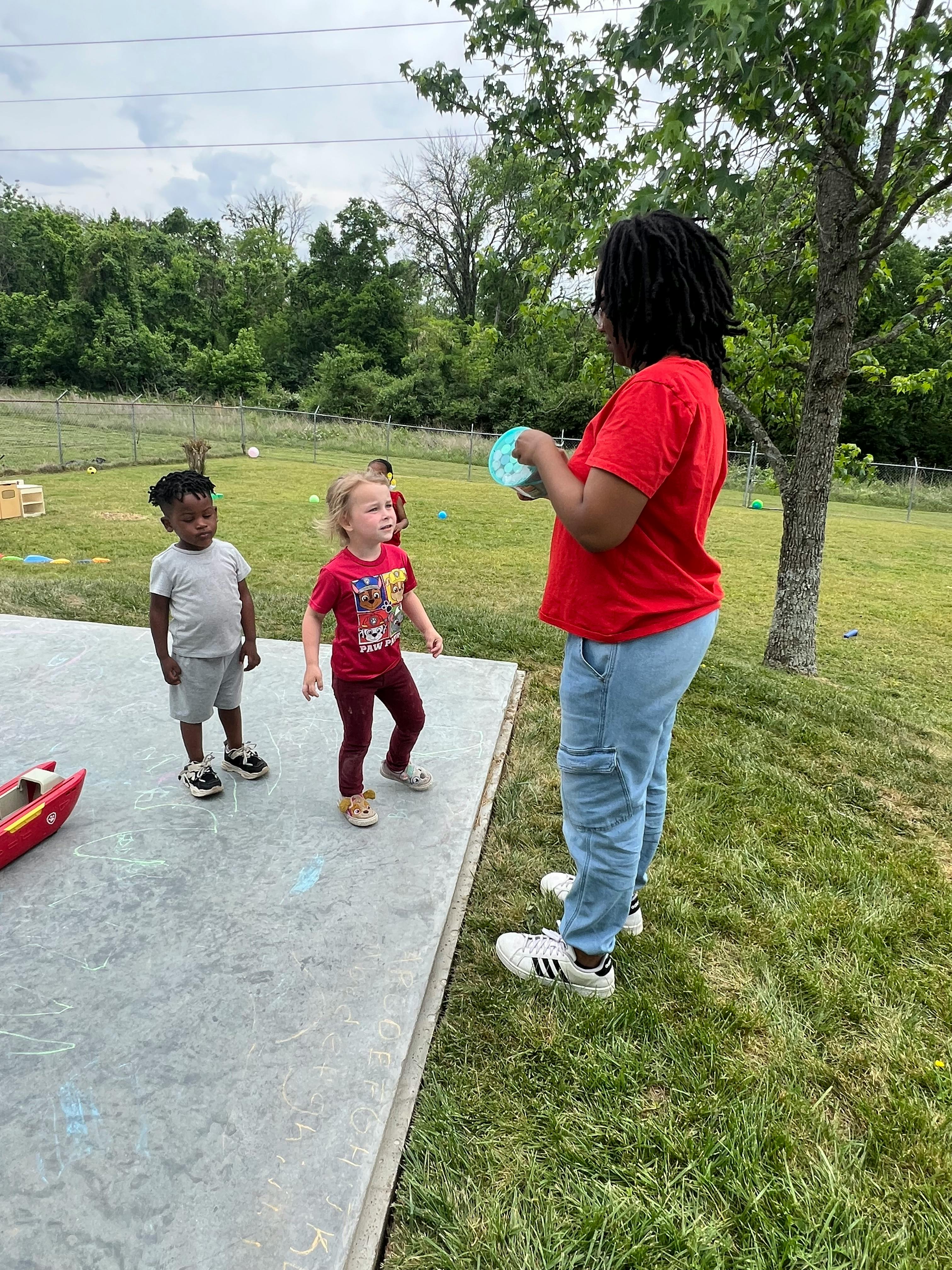 Person holding a bucket with two children standing on chalk drawings