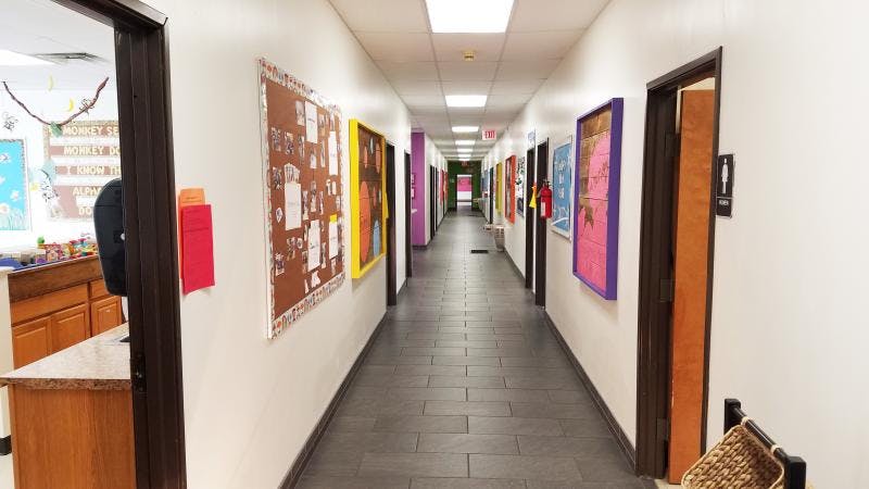 Long school hallway with bulletin boards and doors