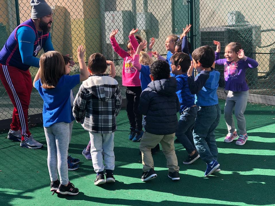 Adult and children playing outdoors with arms raised