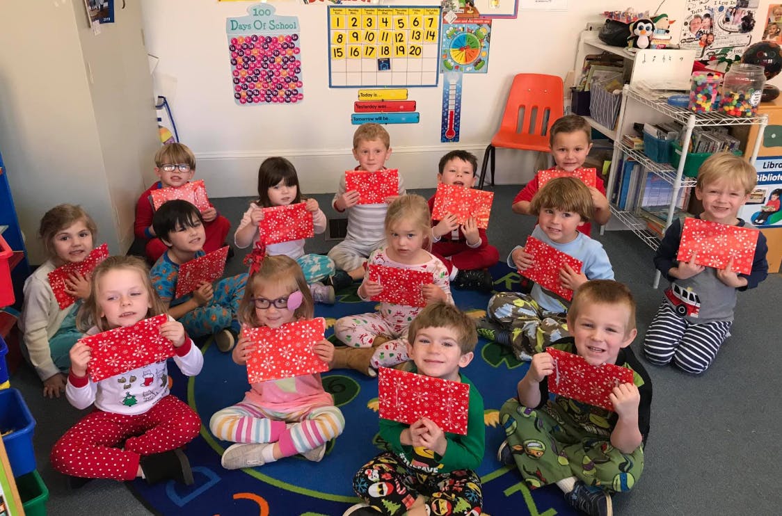 Group of children sitting on the floor holding up red papers