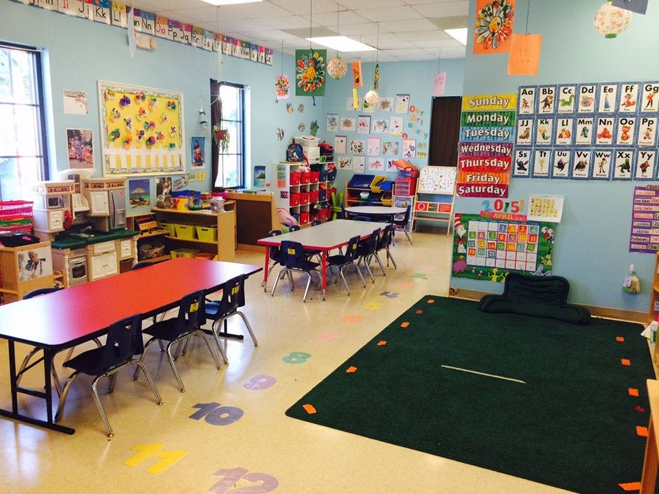 Classroom with tables, chairs, and educational posters on the walls