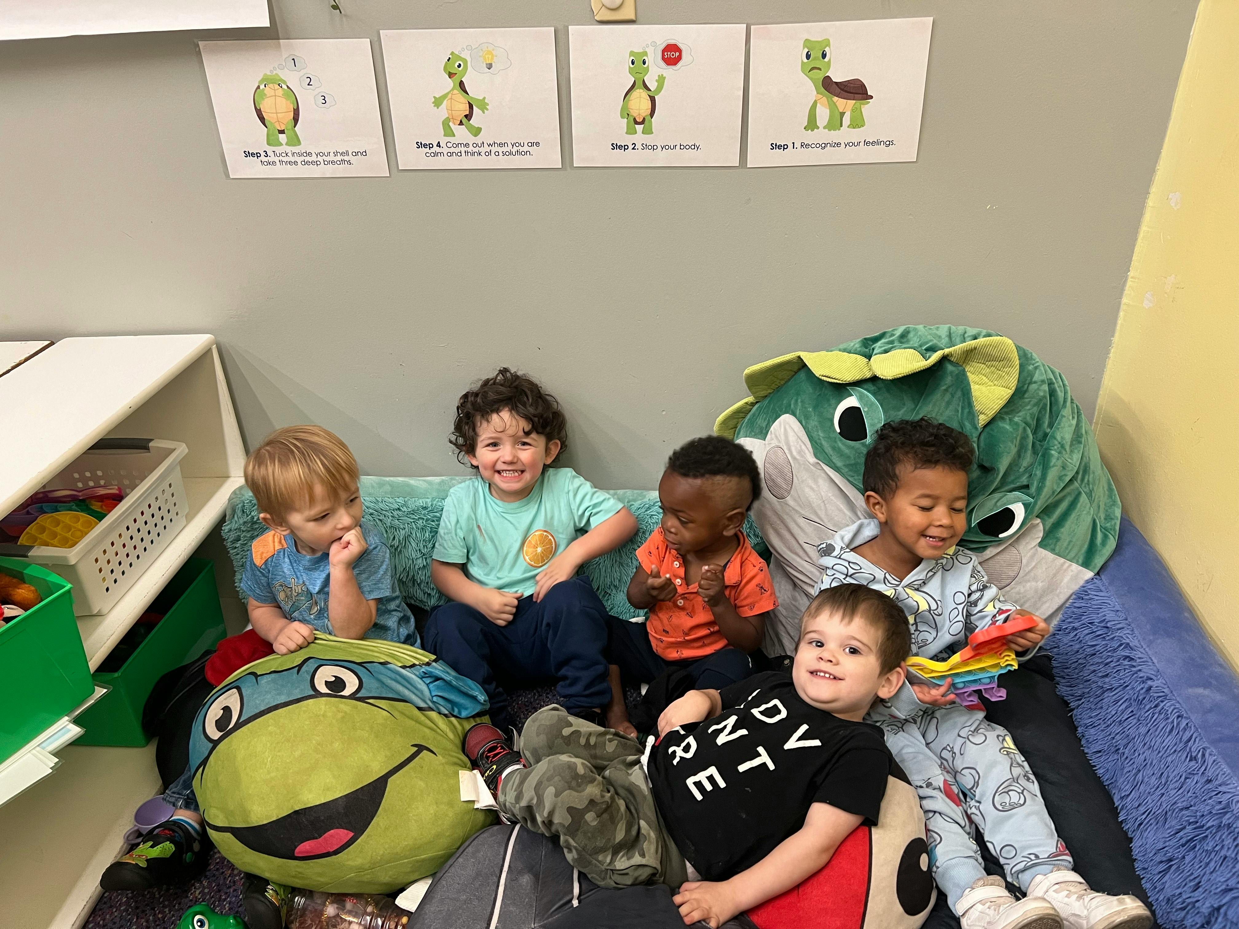 Five children sitting together on a couch with stuffed animals