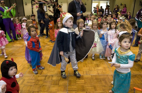 Children in costumes standing on a wooden floor