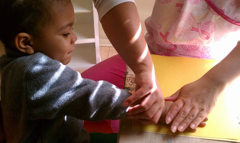 Adult hands helping a child's hands