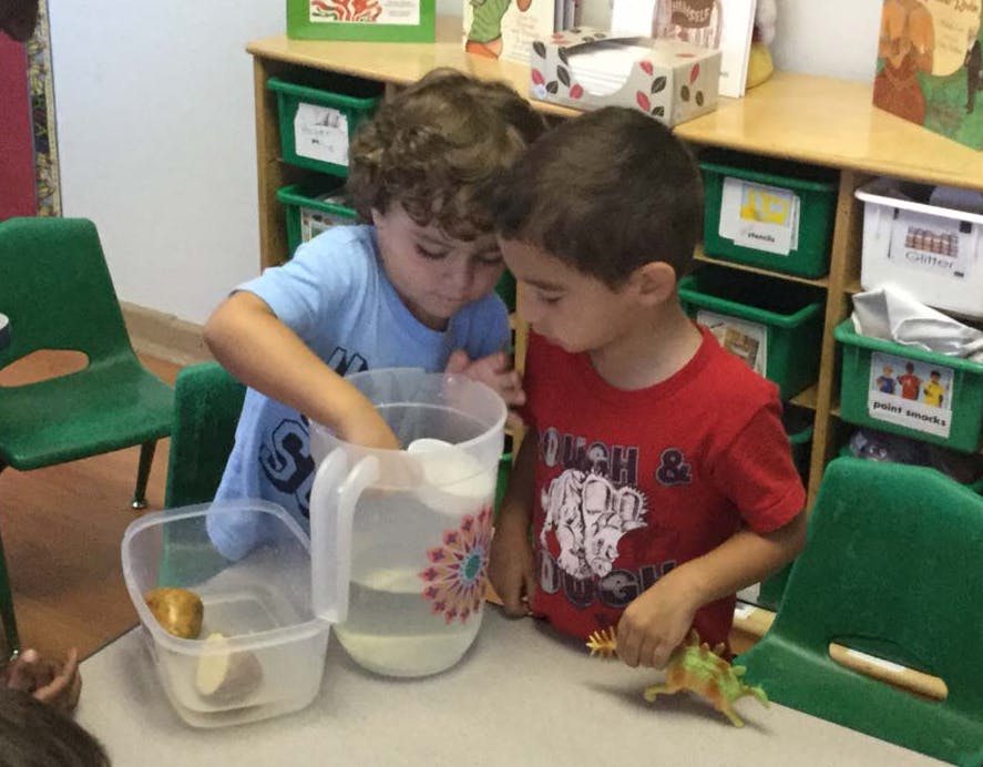 Two children playing with water in a classroom