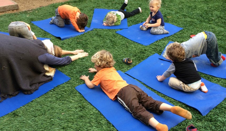 People and children doing yoga on blue mats outdoors