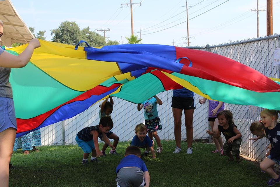 People and children playing with a colorful parachute outdoors
