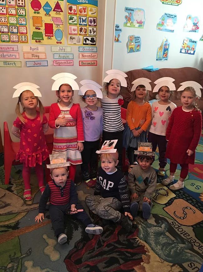 Group of children wearing paper hats in a classroom