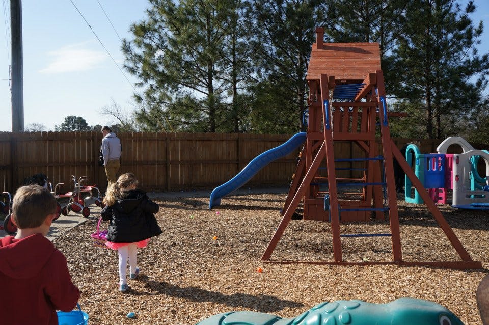 Children and adults on a playground with a wooden playset and slide