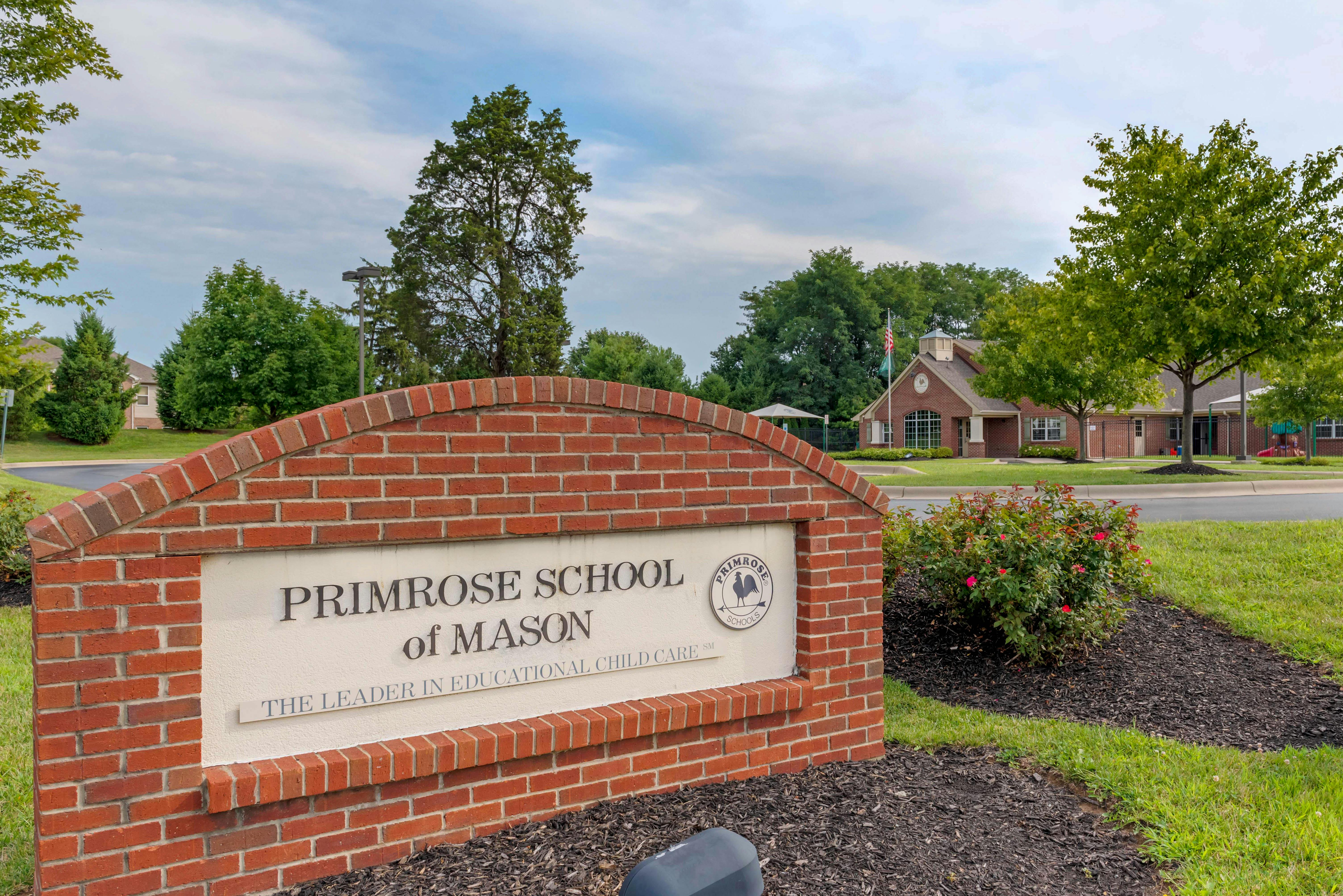 Brick sign with text "Primrose School of Mason" in front of a building