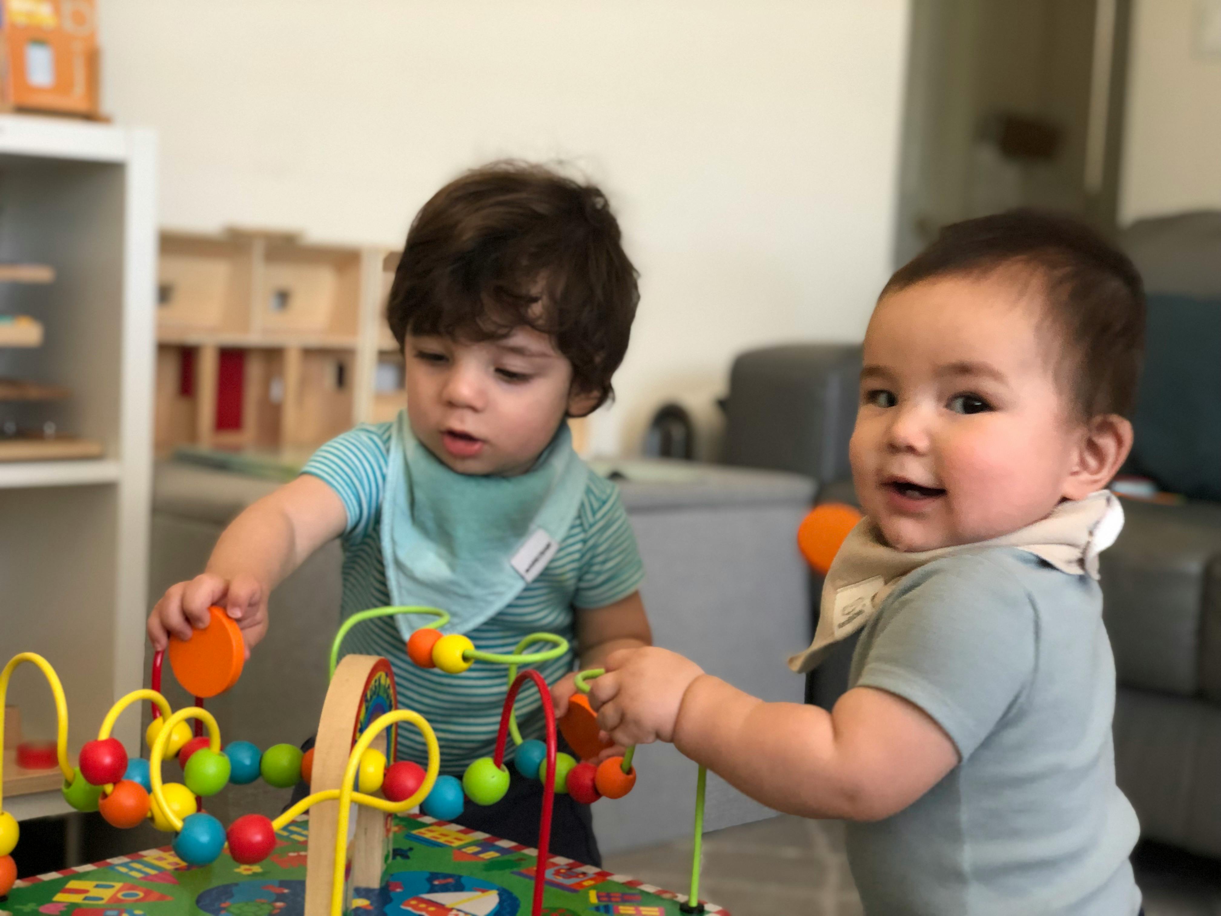 Two children playing with a bead maze toy