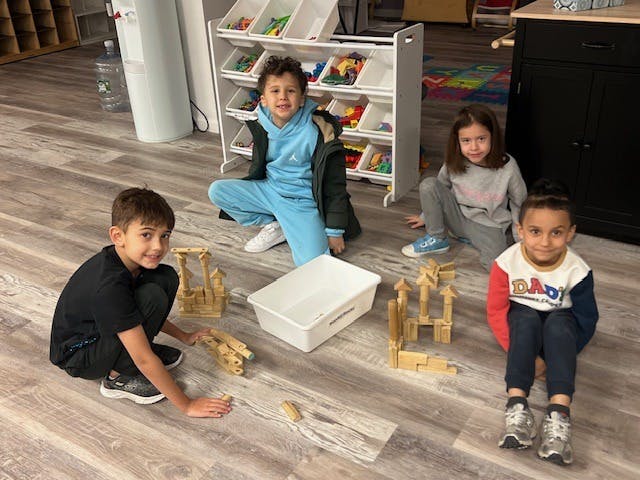 Four children playing with wooden blocks on the floor