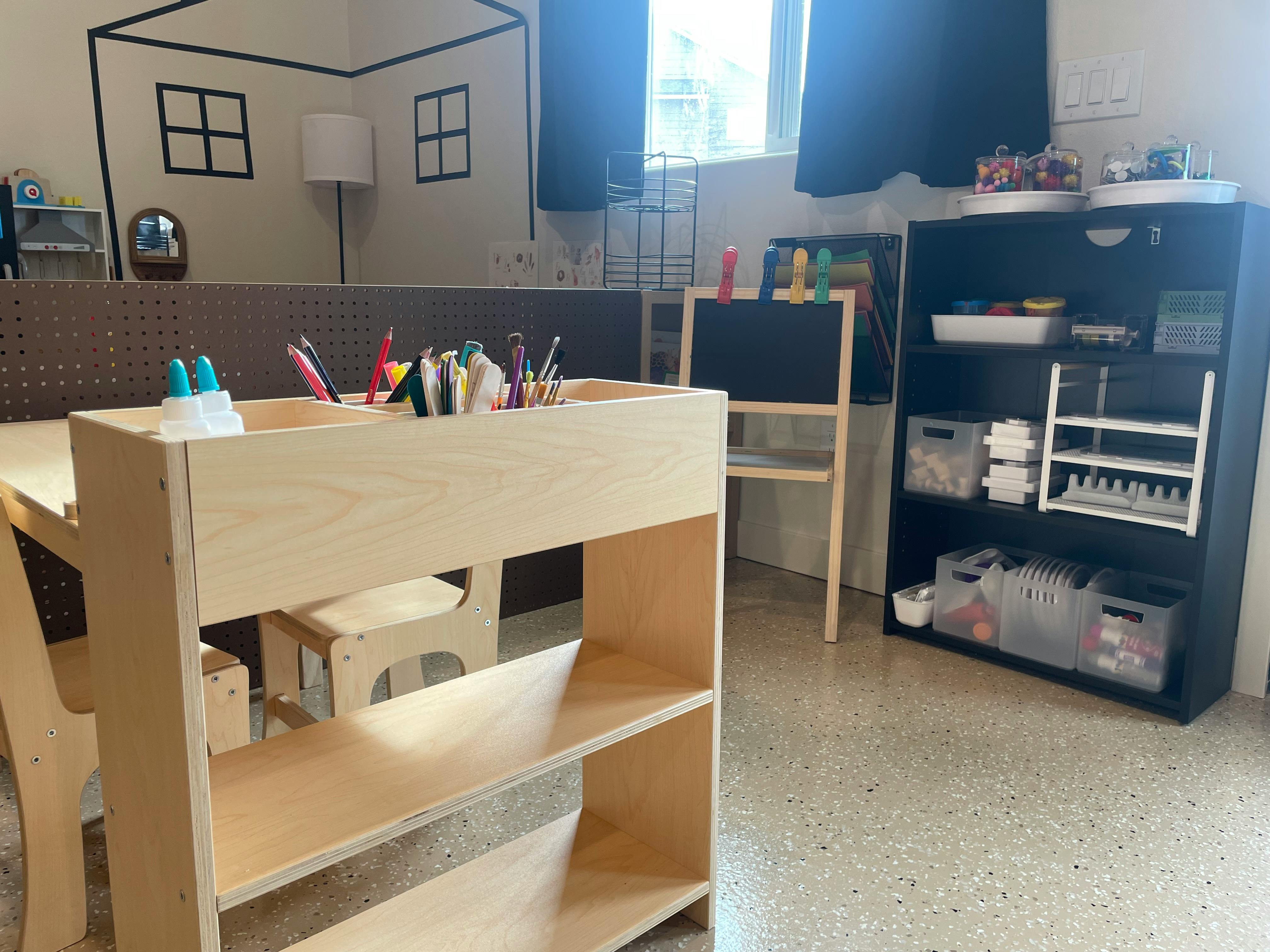 Classroom with a wooden table and shelves, and a blackboard easel