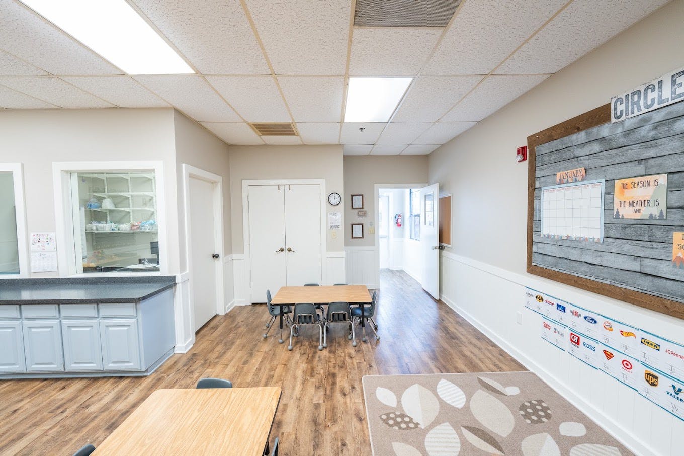 Classroom interior with small tables and chairs and an educational wall display