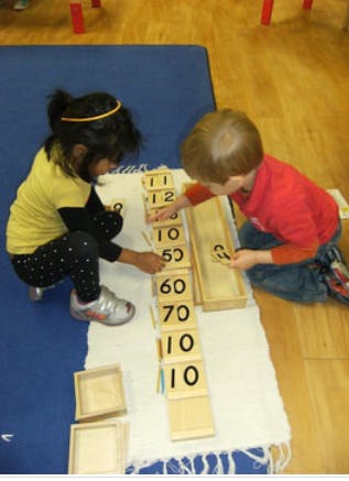 Two children playing with number blocks on a mat