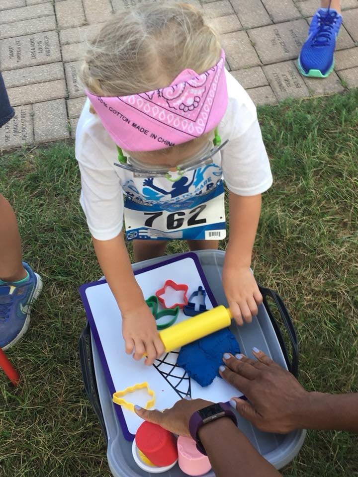 Child with race bib 762 playing with playdough and cookie cutters
