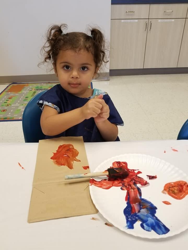 Child sitting at a table with paint supplies