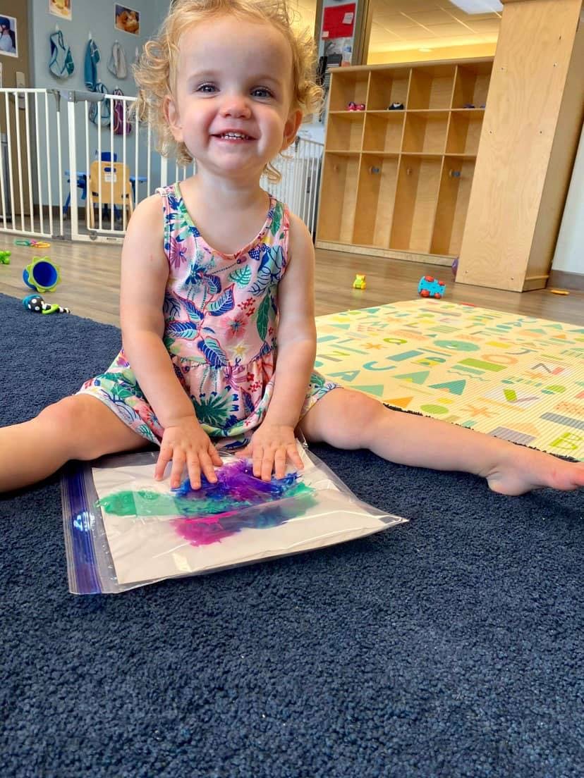 Child sitting on floor playing with a colorful sensory bag
