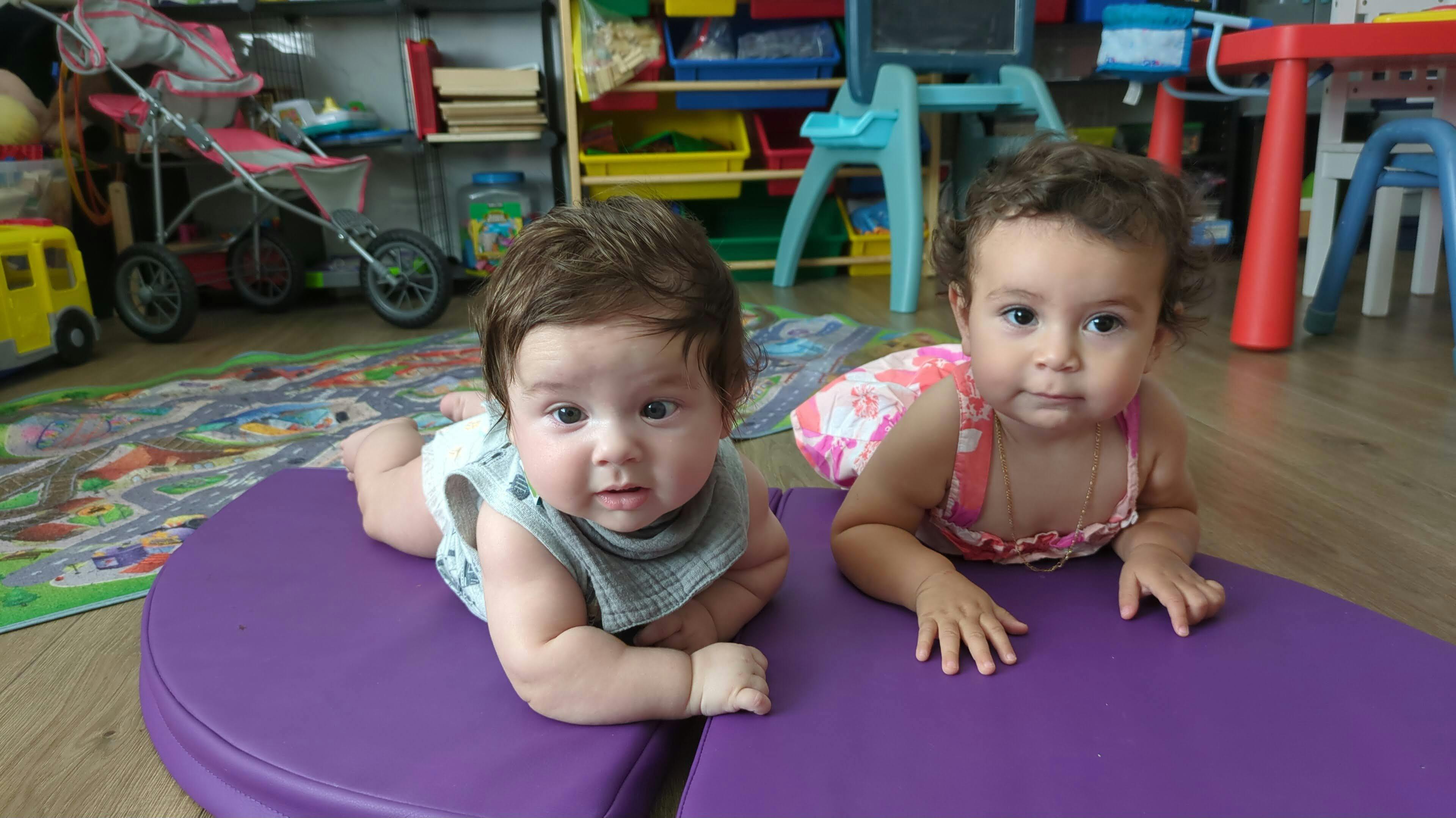 Two babies lying on purple mats