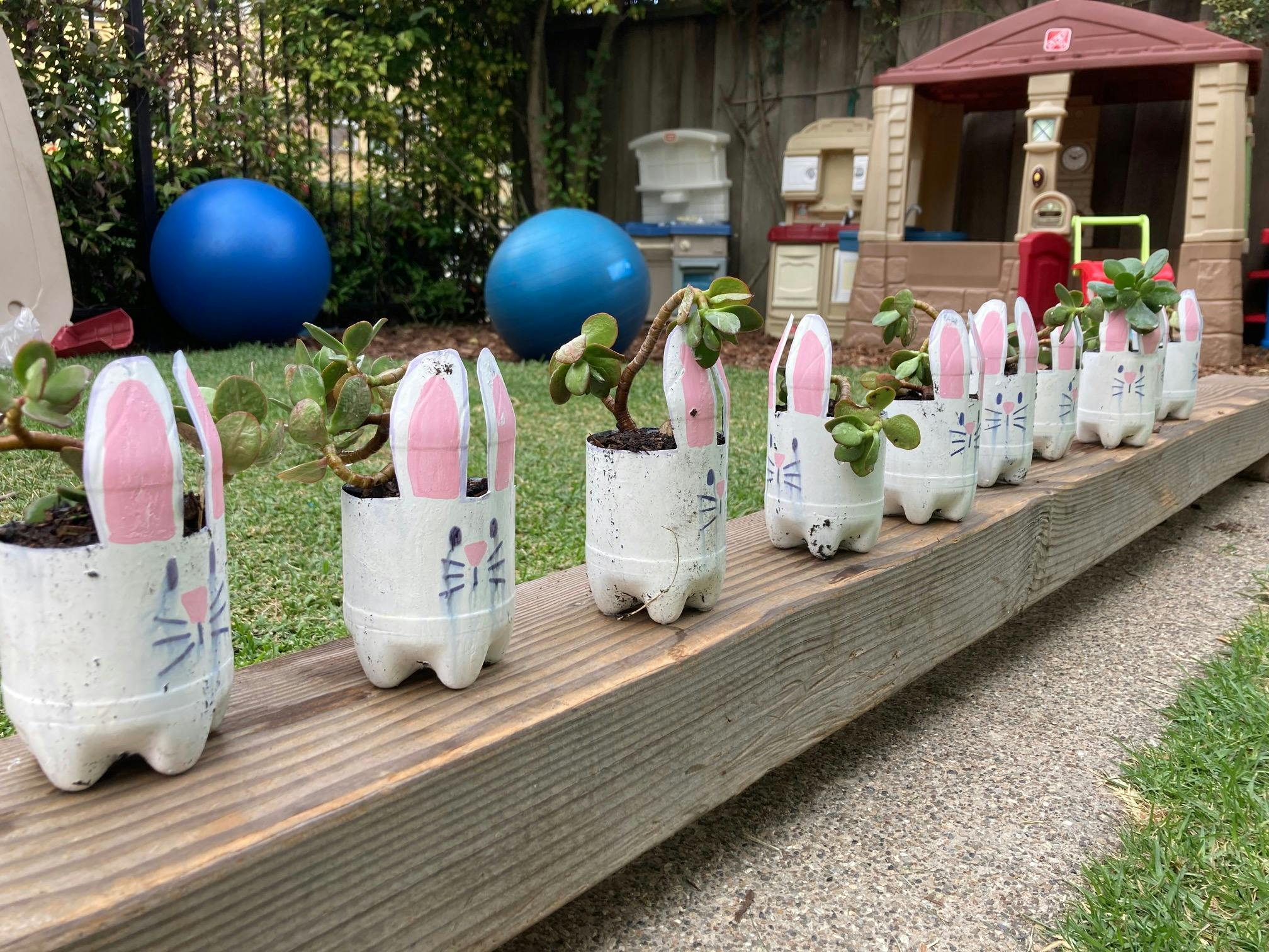 Row of bunny-shaped planters made from plastic bottles with plants