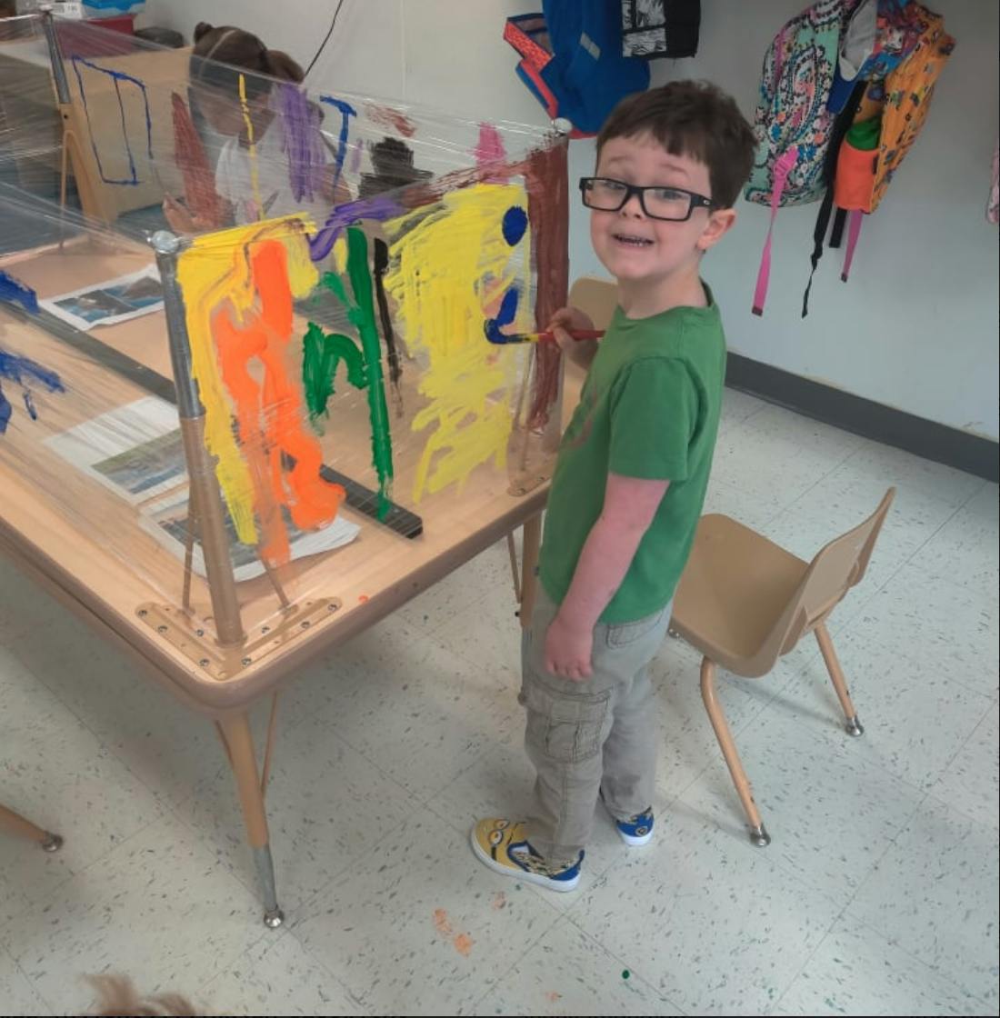 Child painting on a clear easel in a classroom