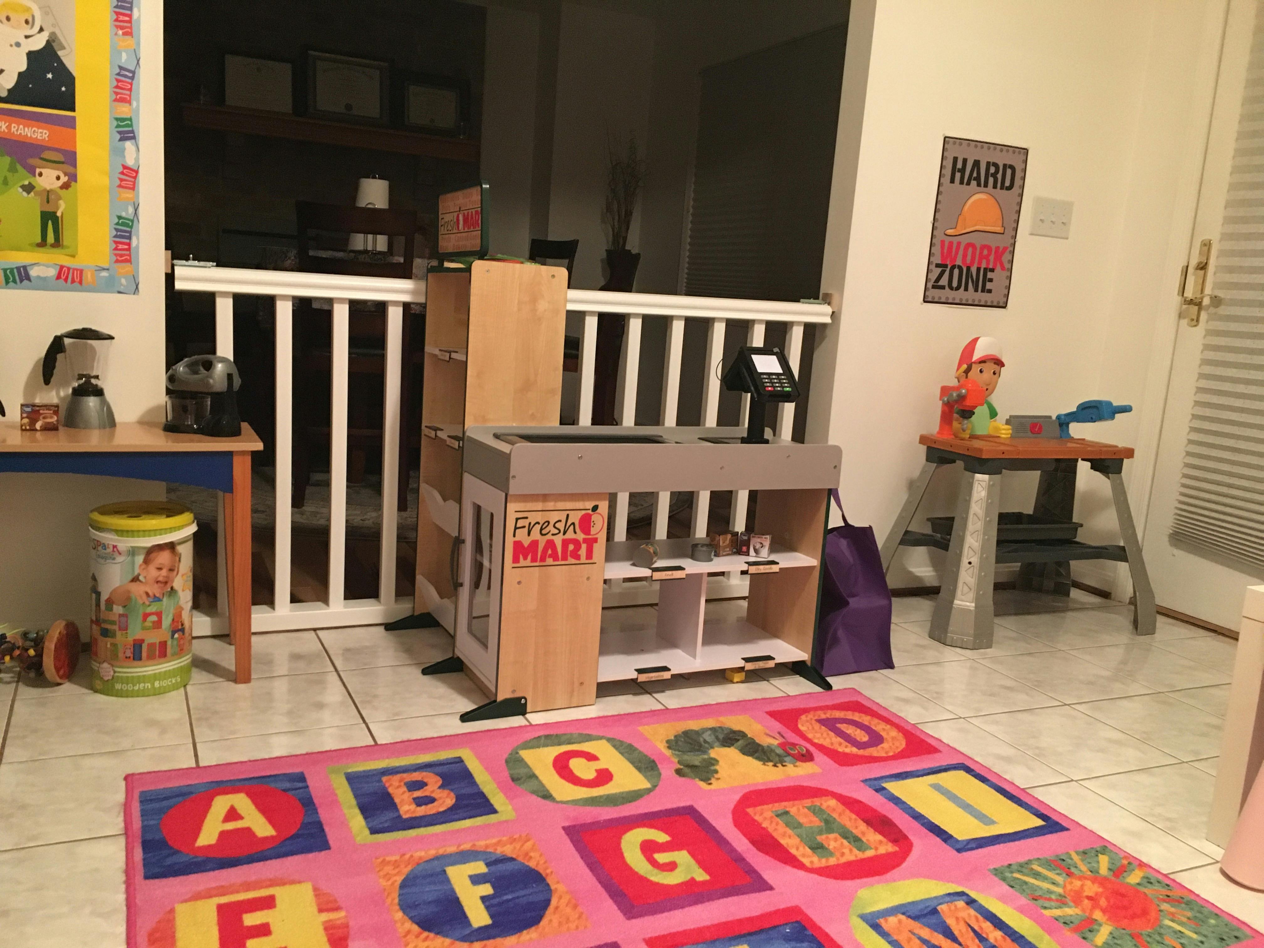 Playroom with toy grocery store and alphabet rug