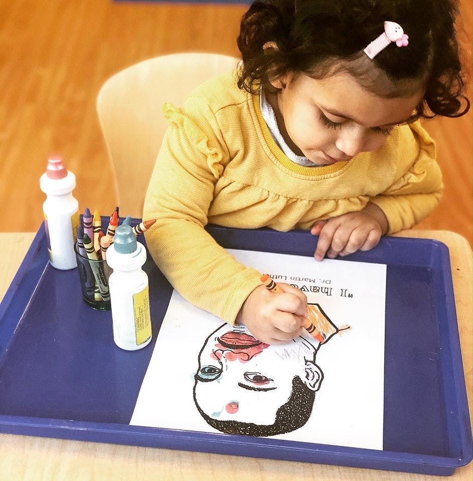 Child coloring a drawing of a face
