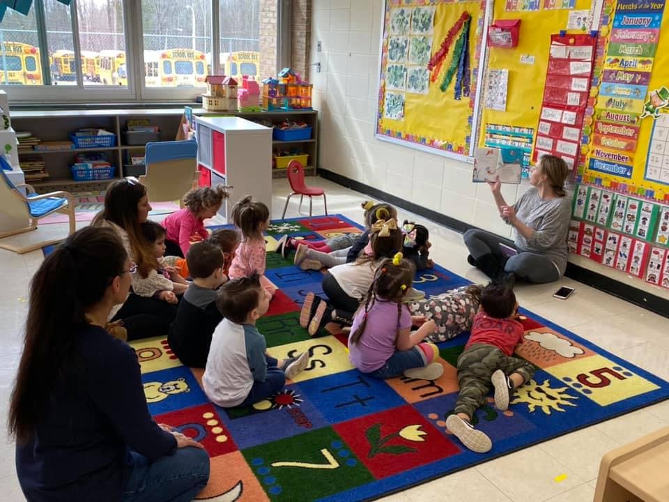 Adult reading a book to children in a classroom