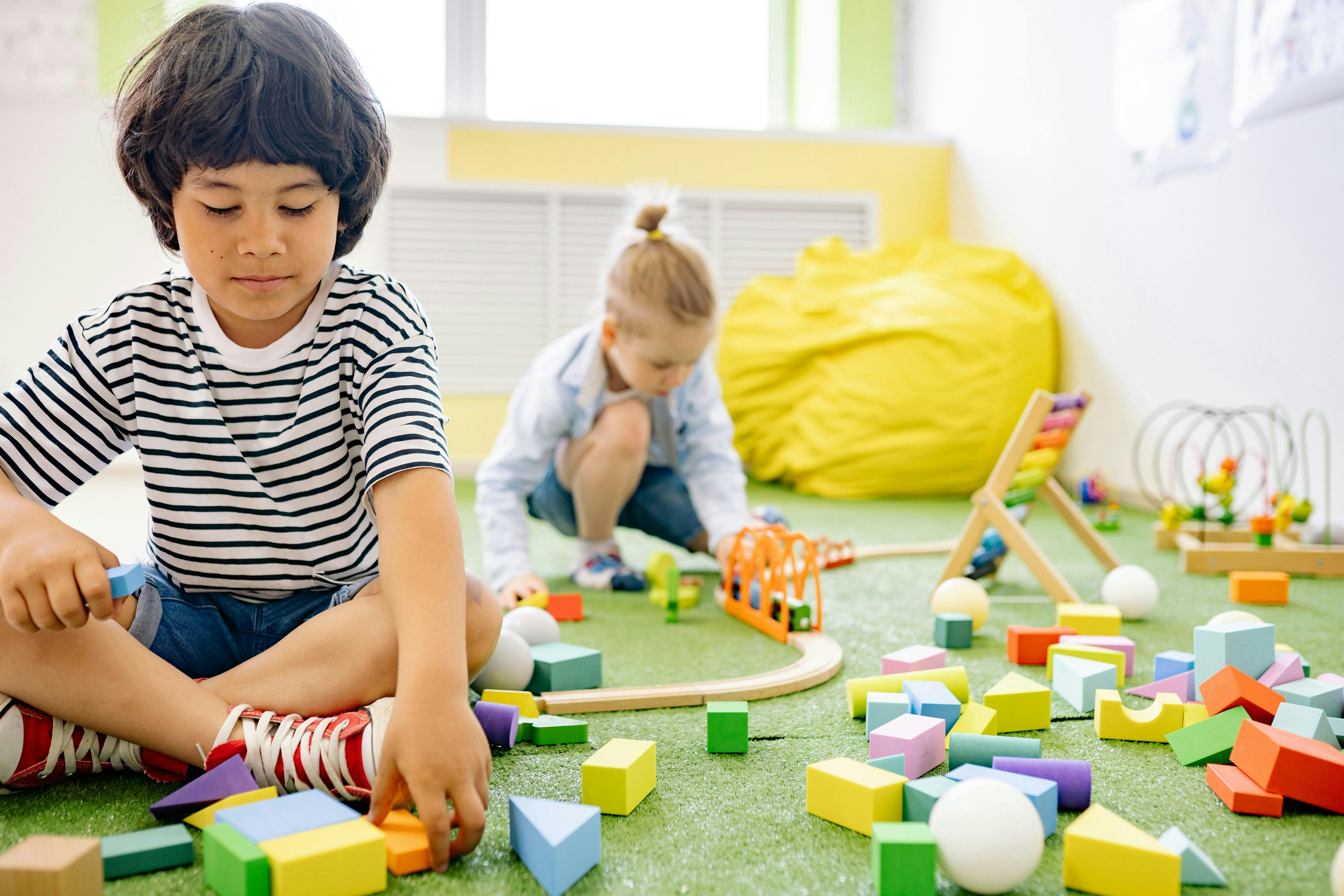 Two children playing with colorful building blocks on the floor