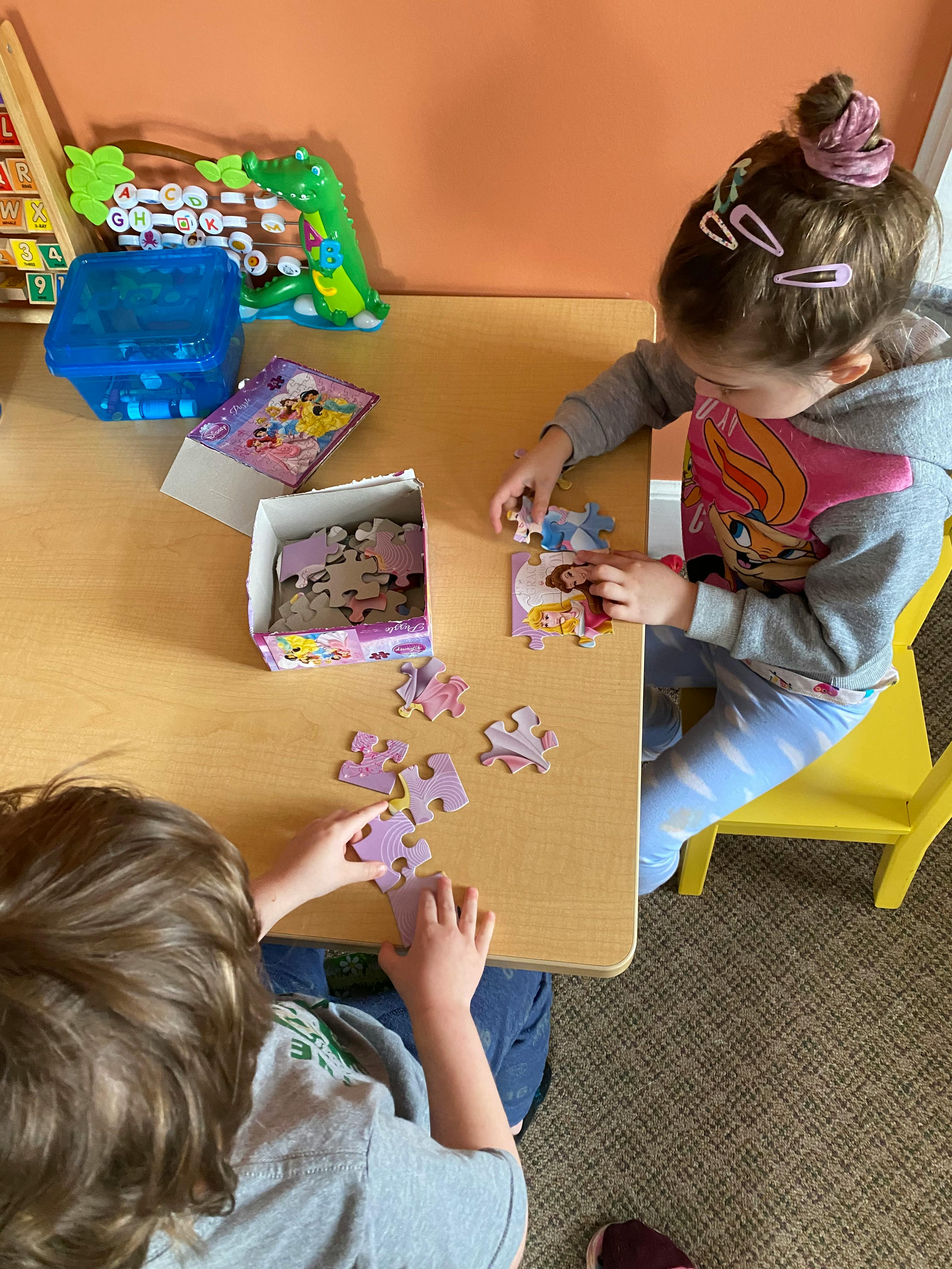 Two children playing with puzzles at a table