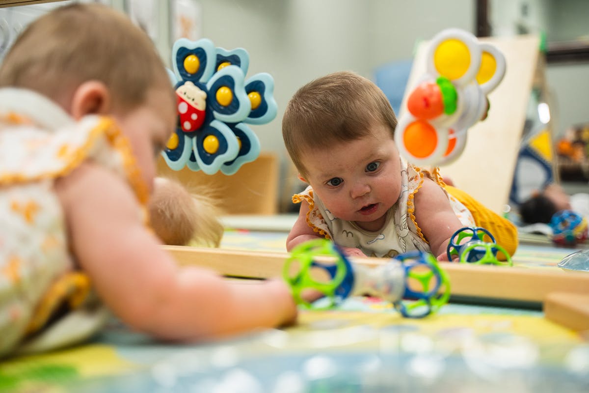 Two babies on a playmat with toys