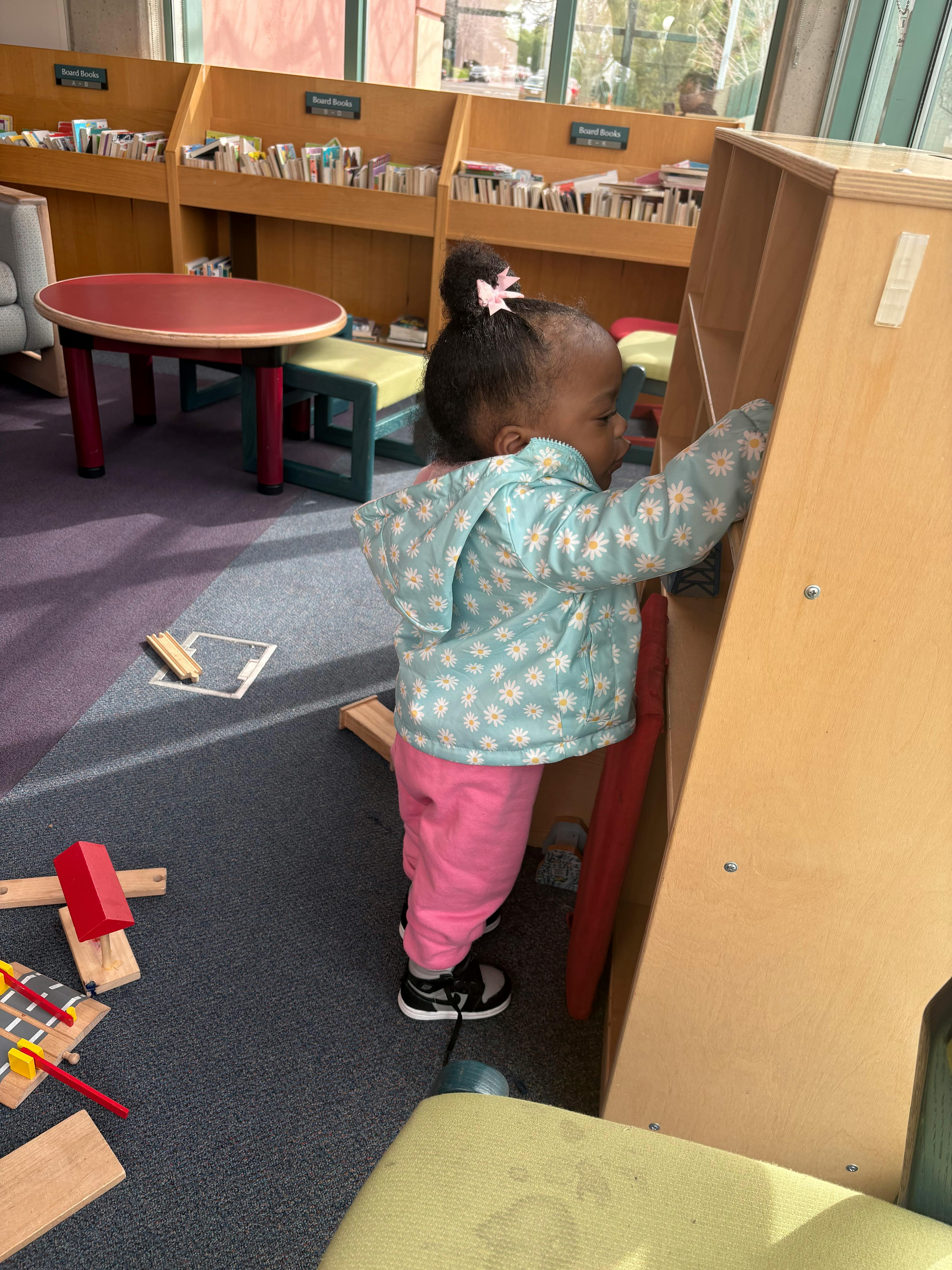 Child standing next to a wooden shelf