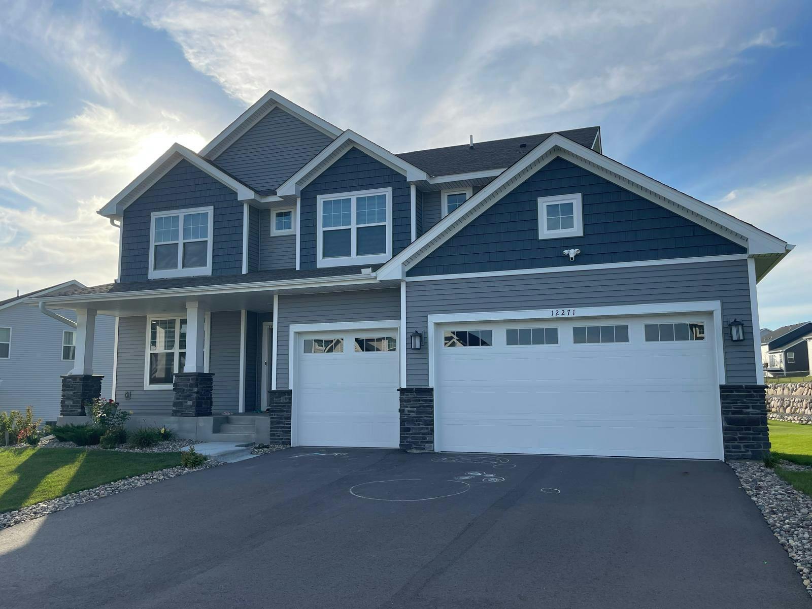 Two-story house with blue and gray siding and two white garage doors