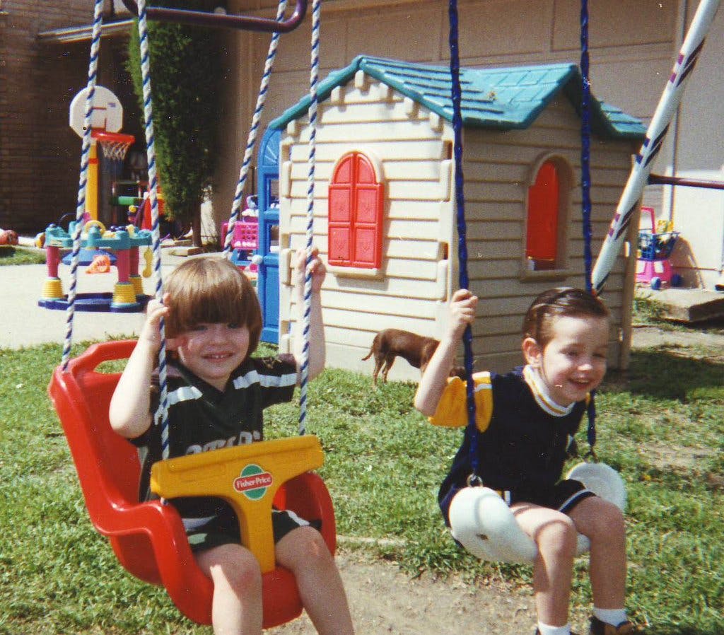 Two children on swings in a yard