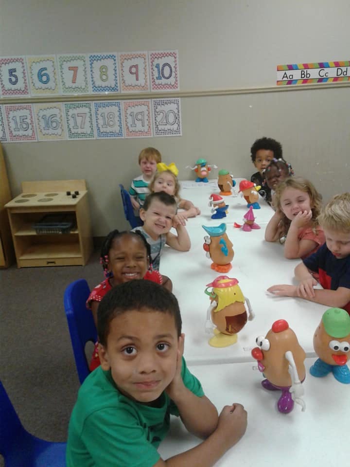Children sitting at a table with Mr. Potato Head toys