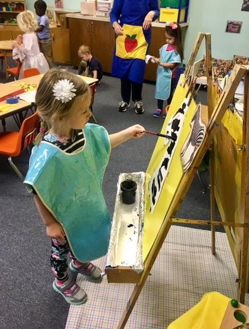 Child painting at an easel in a classroom