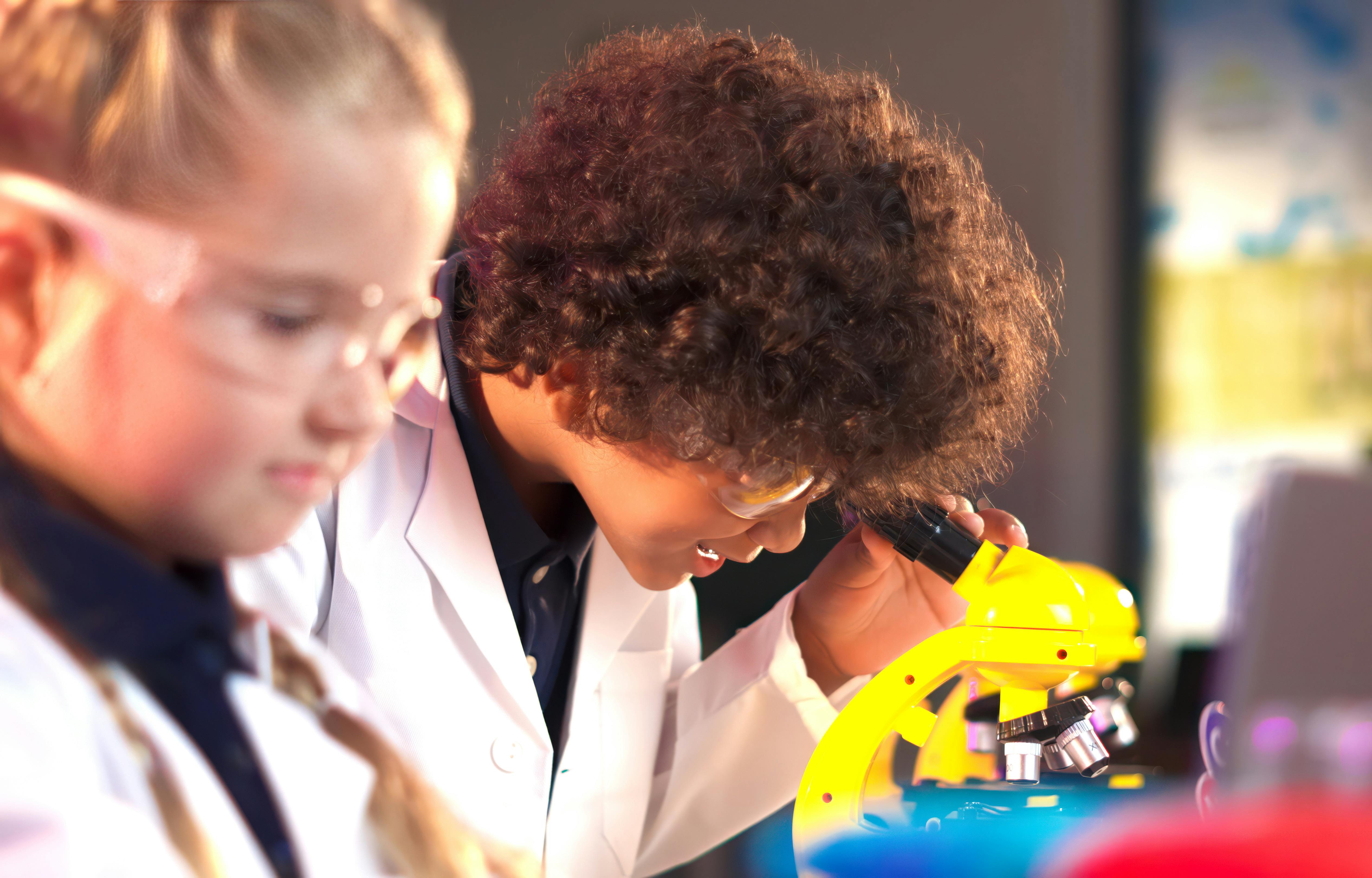 Two people in lab coats looking at a microscope
