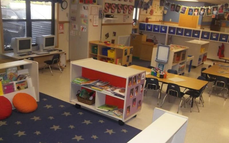 An empty classroom with desks, chairs, computers, and bookshelves
