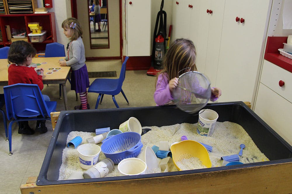 Child playing in a sand table with toys