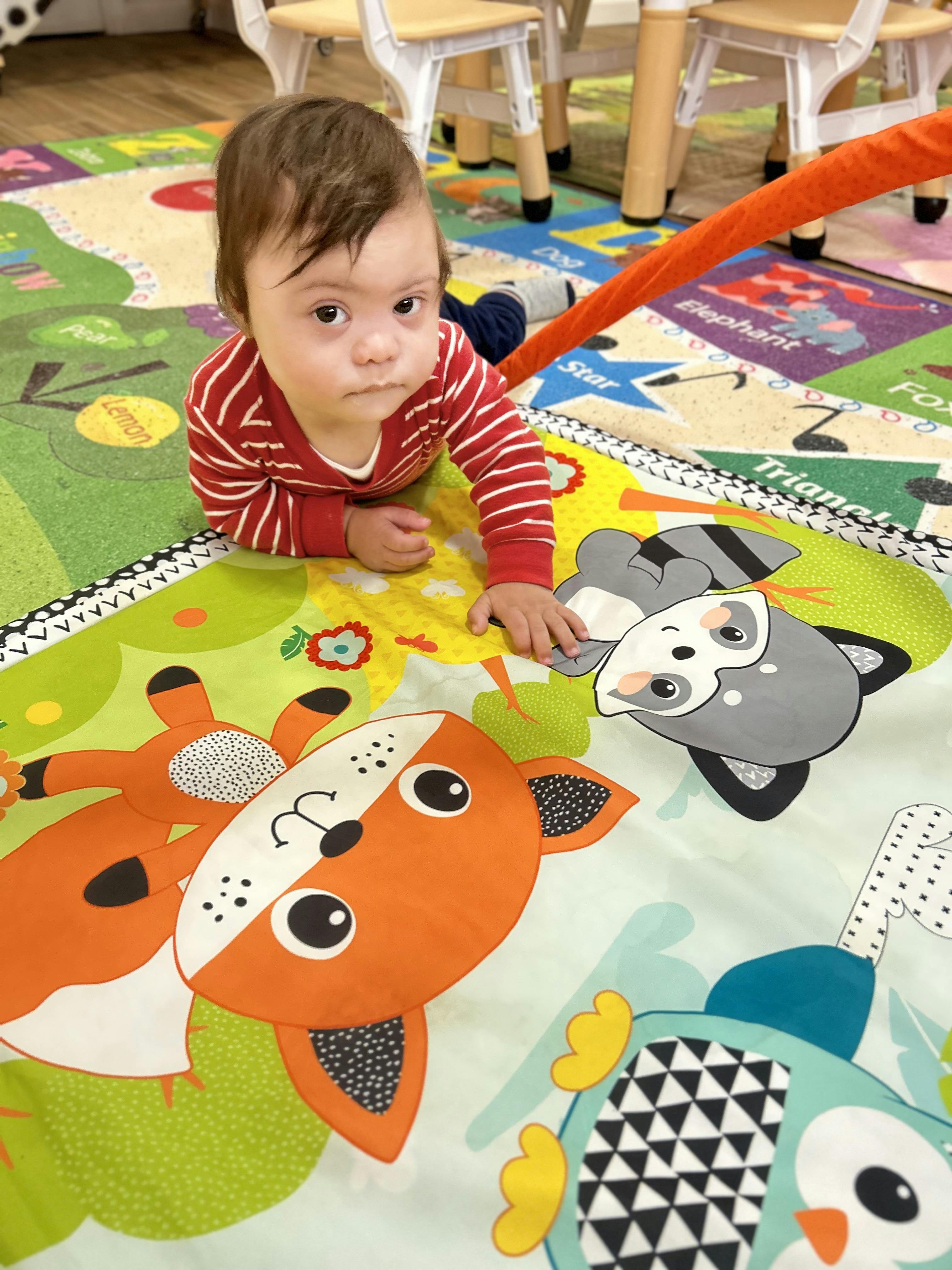 Child lying on a playmat, looking up at the camera